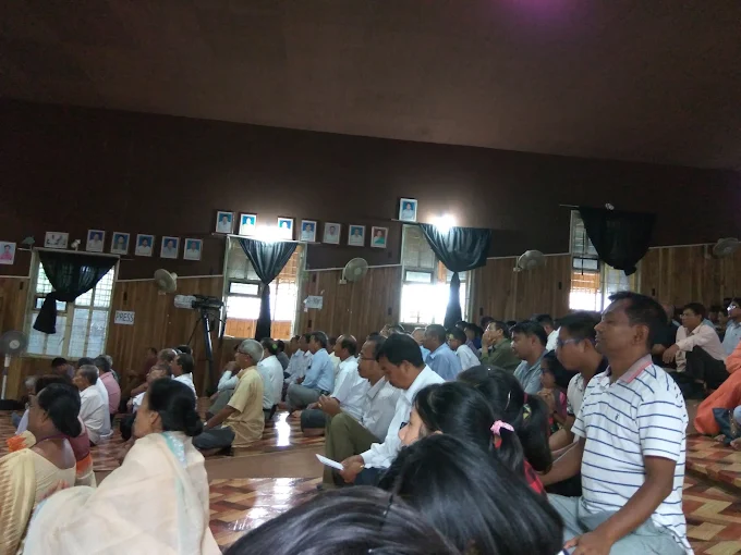 Community members seated on the auditorium floor during a programme.